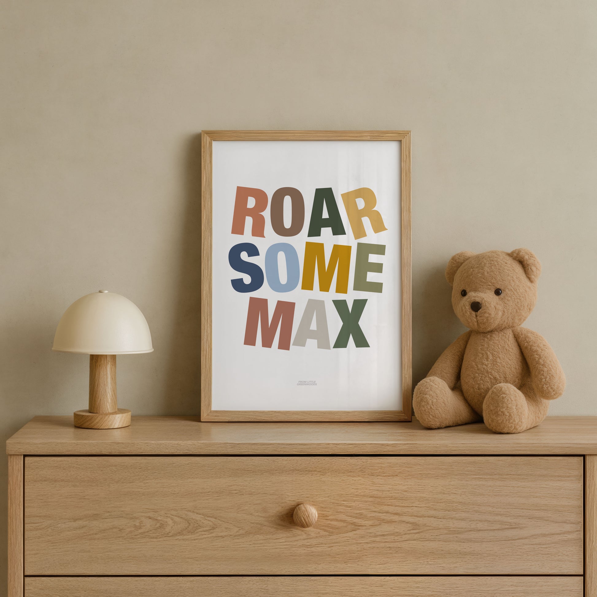 Framed artwork with 'ROAR SOME MAX' text on a wooden dresser with a teddy bear and lamp.