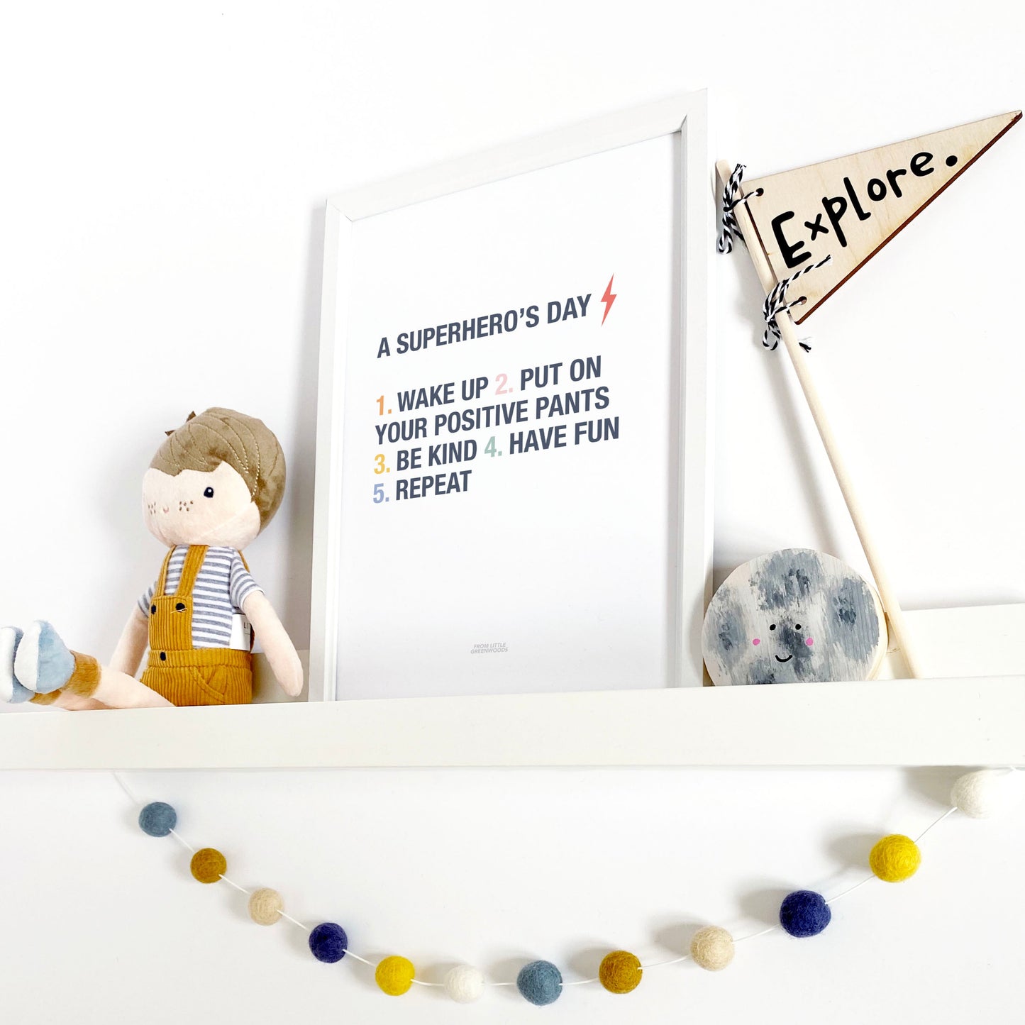 Children's room decor with a shelf featuring a plush toy, framed quote, and decorative flags.