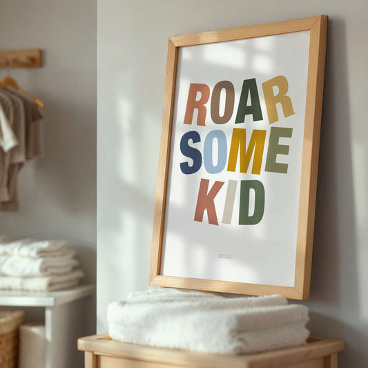 Framed poster with 'ROAR SOME KID' text in a room with folded clothes and a basket.